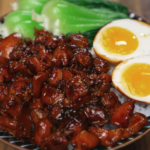 Bowl of Coca Cola braised chicken served over rice with bok choy and jammy eggs — sweet, sticky, and rich chicken dinner.